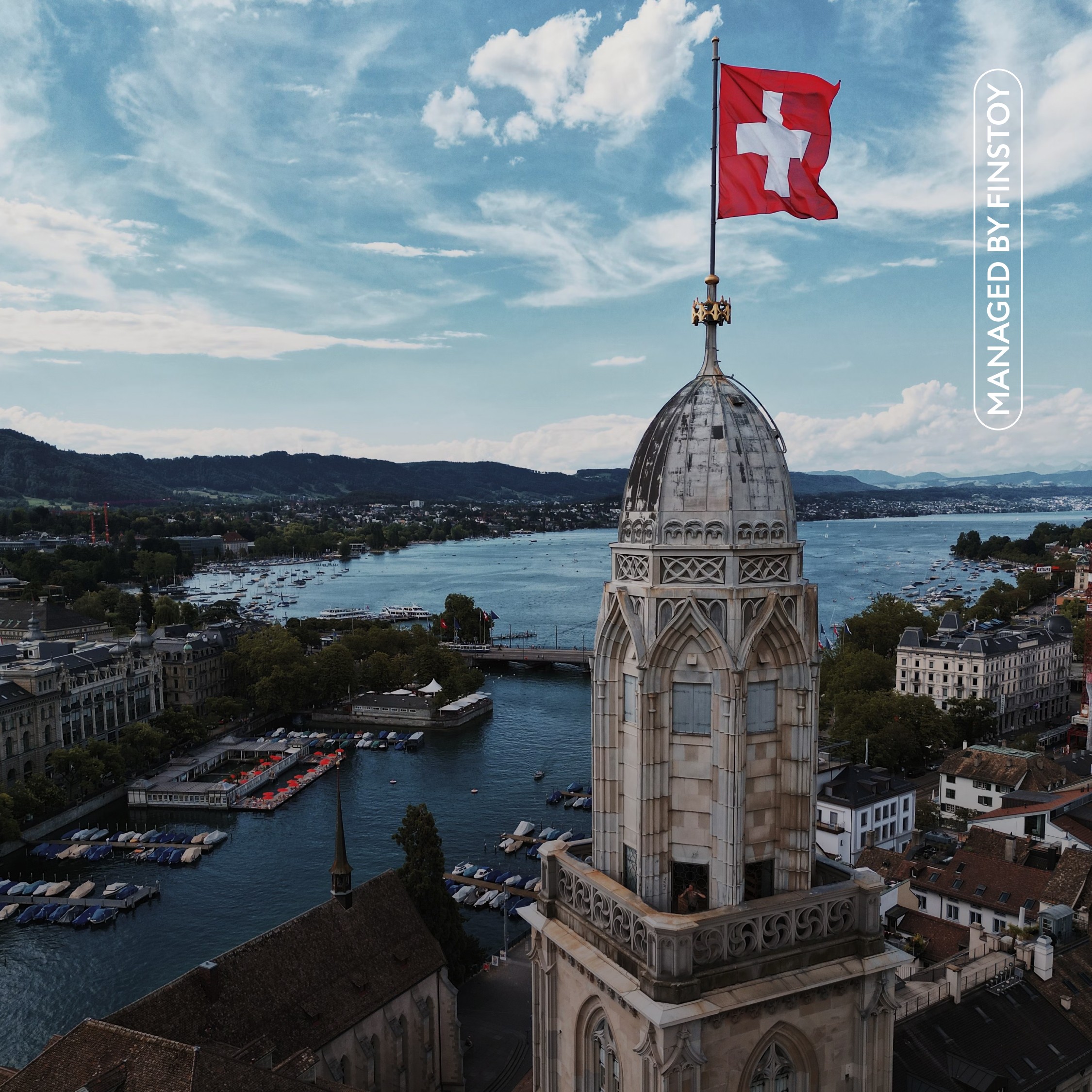 A view of a Swiss lakeside with a beautiful building decorated with a Swiss flag